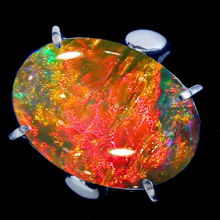 Rounded stone showing vivid red, orange, and green play of color in an open setting.