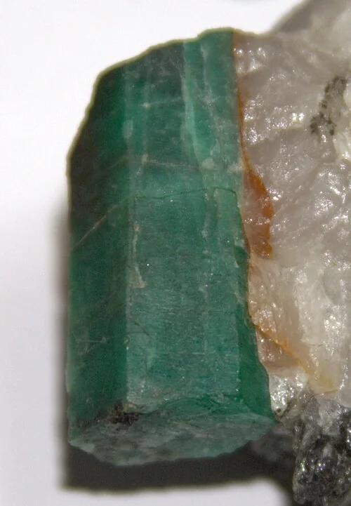 Green prismatic crystal embedded in pale host rock.