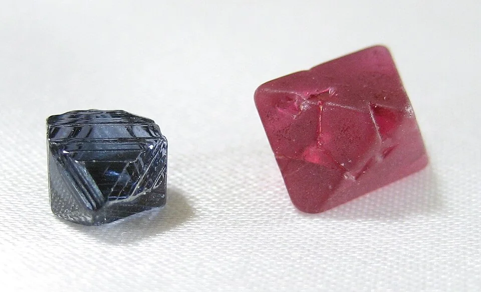 Dark-blue and pink-red octahedral crystals on a pale surface.