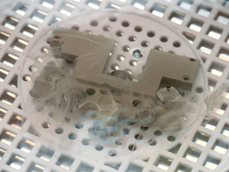 Small items in a perforated basket inside an ultrasonic cleaning bath.